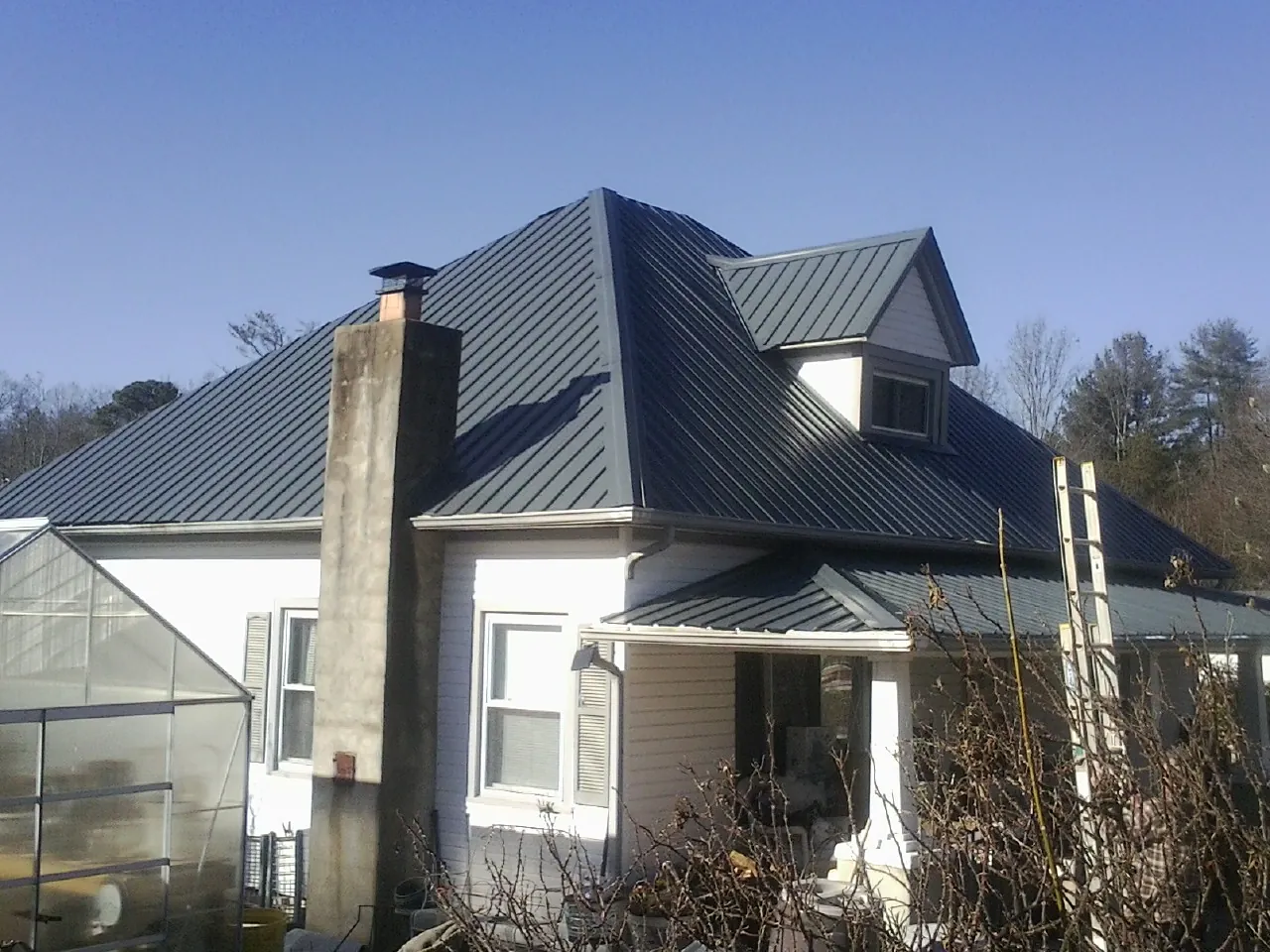 Dark blue standing seam metal roof on a white farmhouse with dormer — Slate & Tile Roof Repair by Roofing Brothers in South Bethlehem
