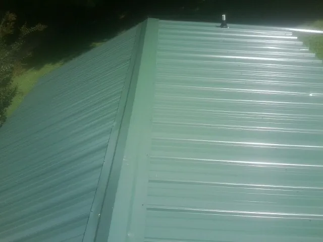 New green metal panels meeting at the ridge of a roof — Flat Roof Repair work by our crew in South Bethlehem