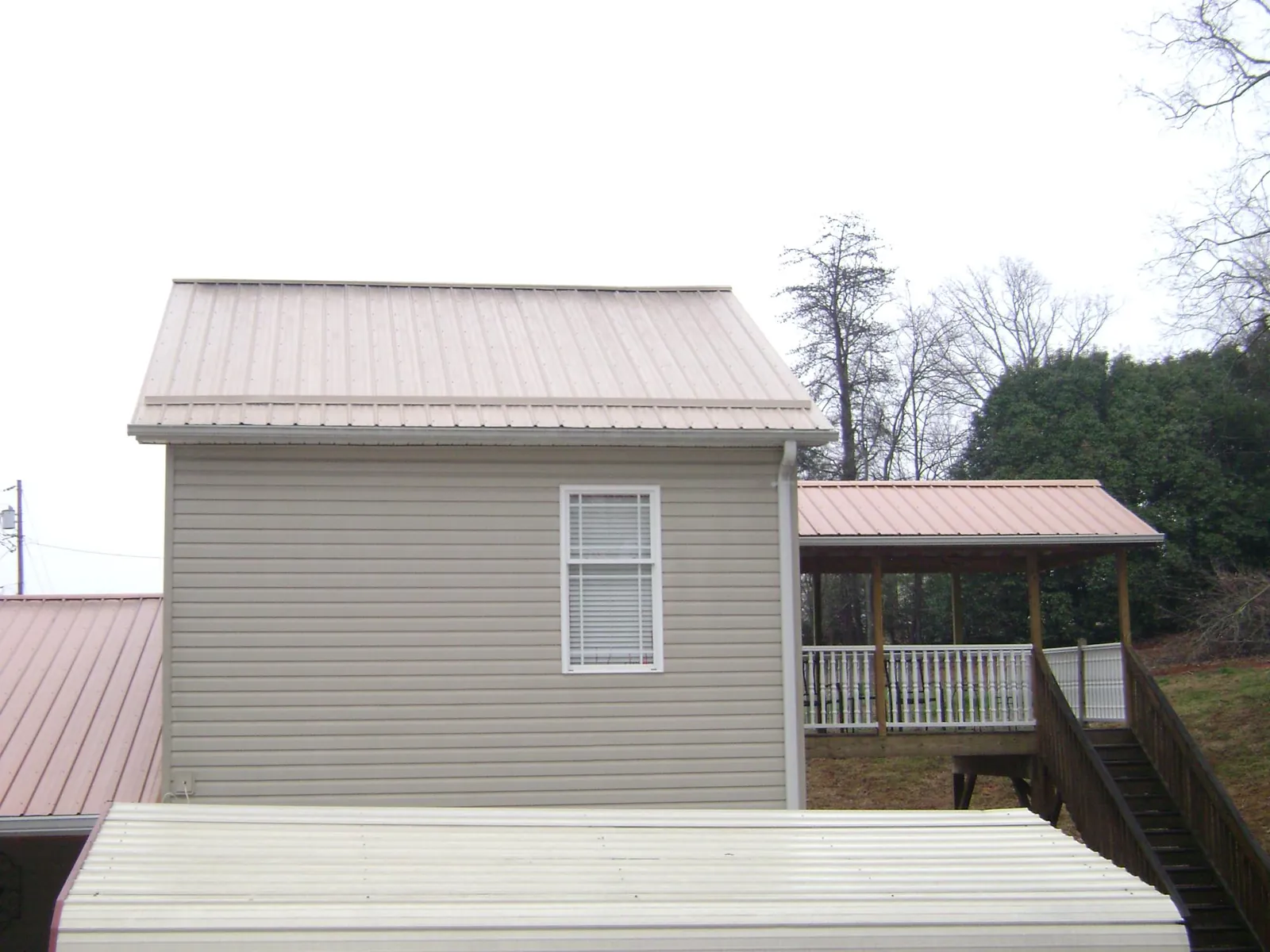 Tan metal roofs on a two story addition and attached porch, from a Roof Replacement job in South Bethlehem