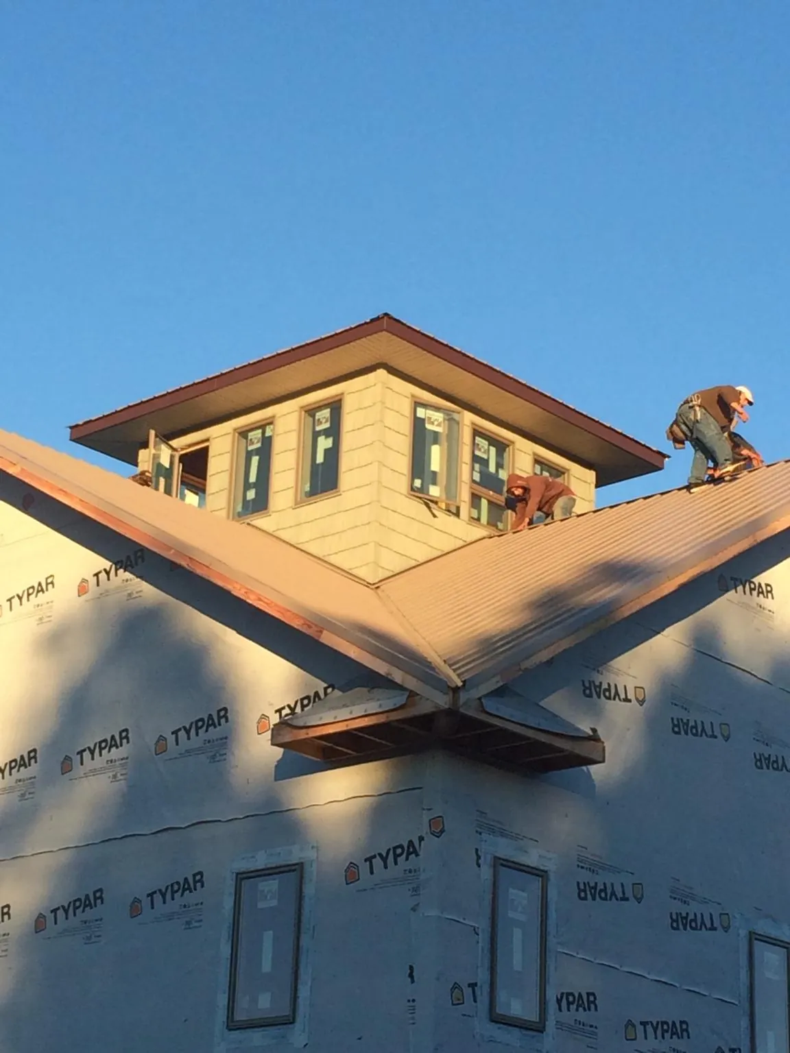 Roofers working around a rooftop cupola on a new metal roof at sunset — Roof Waterproofing in South Bethlehem by Roofing Brothers